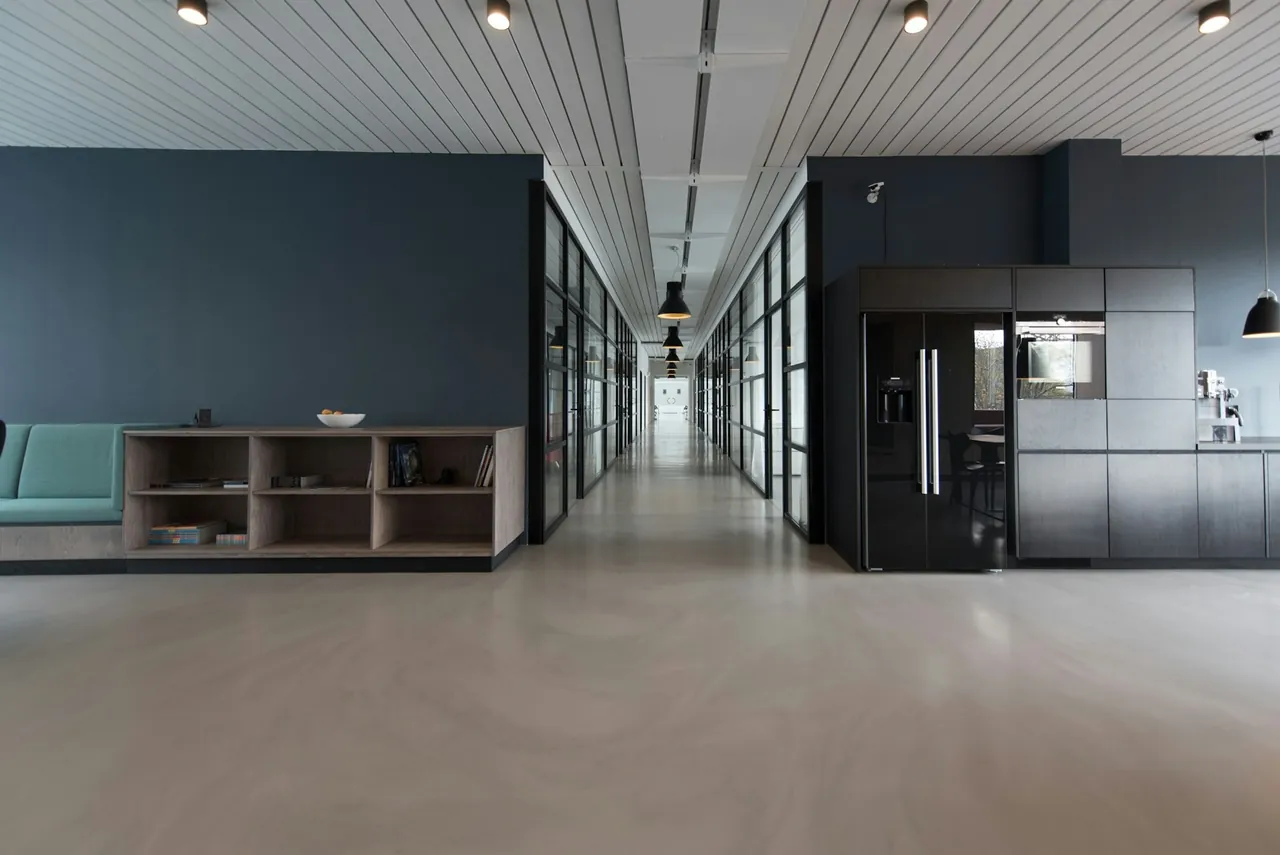 An empty open-plan office with a long glass-walled corridor
